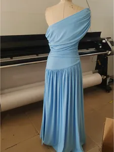 Detail shot of an elegant light blue one-shoulder ruched maxi dress displayed on a dress form