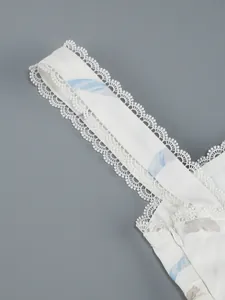 Détail de la bandoulière en dentelle blanche sur une robe à fleurs imprimée