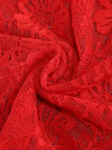 Macro shot showing the intricate texture of the red floral lace fabric for evening dress