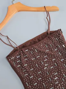 Dettaglio macro di strass argentati scintillanti su un mini abito da sera marrone chic.