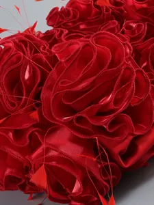 Close-up detail of red 3D floral ruffles on evening dress fabric texture showing sheen.