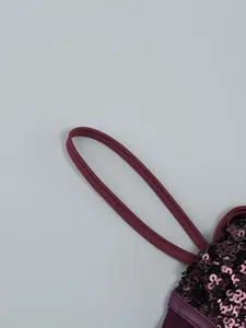 Close-up of elegant burgundy sequin dress showing fine strap and sparkling texture
