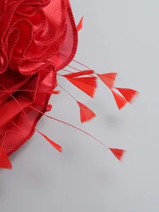 Close-up detail of red 3D floral fabric and delicate feathers on evening party dress