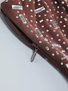 Dettaglio di abito marrone in rete con strass scintillanti e zip invisibile sul lato