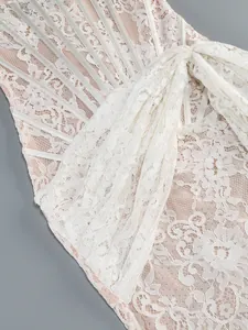 Detailed close-up of white floral lace dress with ribbon and corset boning