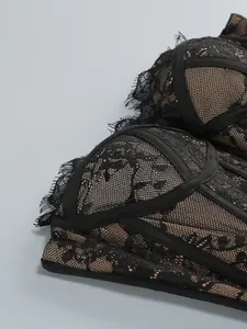 Close-up detail of intricate black lace embroidery and mesh texture on a corset dress.