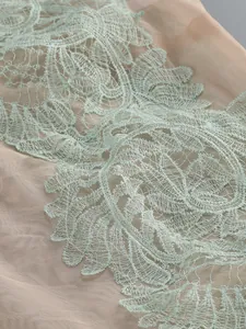 Close-up of intricate mint green floral lace appliqué on nude mesh fabric