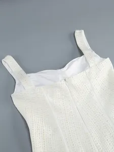 Close-up van witte bodycon jurk met gedetailleerde parelversieringen en ritsdetail