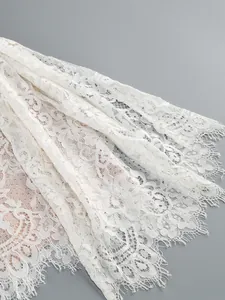 Close-up detail showing the intricate floral texture of elegant white eyelash lace fabric.