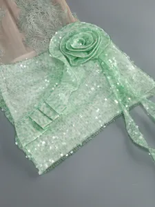 Macro view of mint green sequin texture and intricate 3D fabric flower decoration