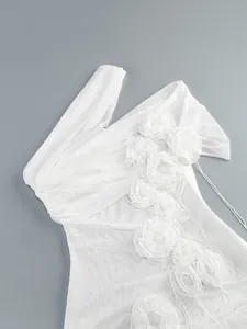 Detailed view of 3D fabric flowers and mesh texture on white one-shoulder dress.