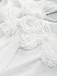 Close-up of white mesh dress featuring 3D fabric flowers and intricate beaded centers