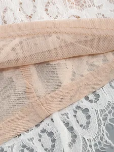 Close-up of the delicate white lace and nude mesh stitching on the elegant dress.