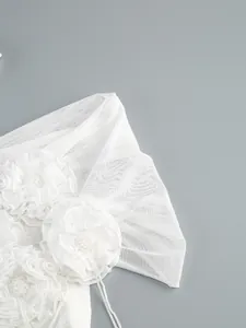 Close-up detail of white mesh fabric with intricate floral accents and beadwork