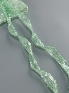 Macro view of mint green mesh fabric with shimmering sequins on a dress strap detail.