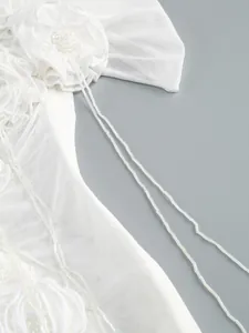 Close-up of white mesh dress with delicate 3D floral applique and beaded details