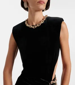 Détail d'une robe de soirée sans manches en velours noir avec découpe latérale et chaîne dorée