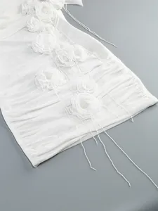 Close-up detail of white mesh bodycon dress with elegant 3D fabric flower decorations.