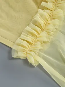 Close-up of yellow mesh fabric and layered ruffle detailing on a sexy evening dress.