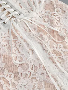 Close-up of white floral lace embroidery and satin ribbon lacing on a corset dress