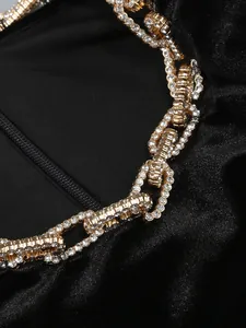 Détail d'une élégante robe de soirée en velours noir avec chaîne ornée de strass brillants.