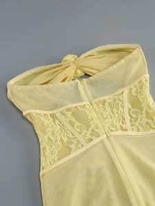 Close-up of delicate floral lace and mesh splicing on a yellow tube top dress.