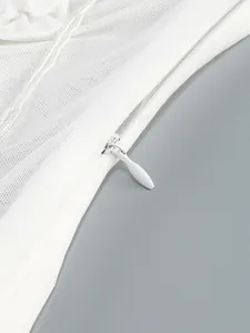 Close-up of hidden zipper on white mesh dress with floral decoration detail.