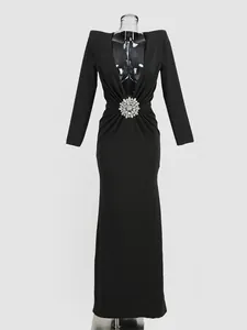 Detailed front view of black long-sleeved deep V evening gown with crystal flower decoration