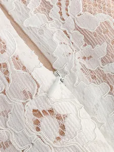 Detailed macro shot of exquisite white floral lace and hidden zipper on an elegant dress