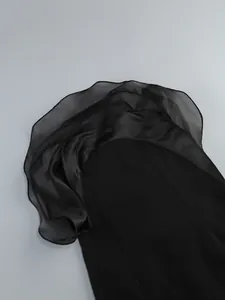 Close-up of black strapless dress featuring layered organza and satin ruffle detail