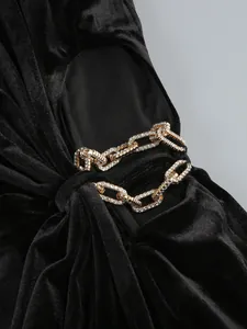 Détail d'une chaîne dorée sertie de strass sur une robe de soirée en velours noir