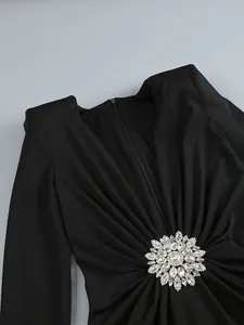 Close-up detail of sexy black deep V-neck dress with crystal rhinestone brooch and pleats