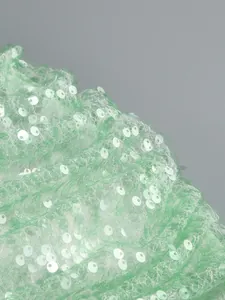 Close-up detail of shimmering light green sequins on mesh fabric for an evening dress