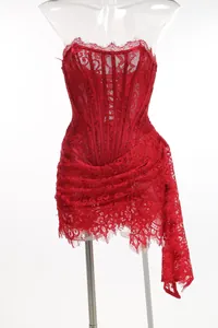 Detail of a red strapless lace corset dress with sheer panels and a side drape