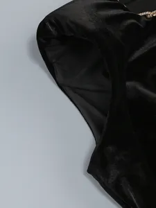 Gros plan d'une robe en velours noir montrant la texture du tissu et les détails strass.