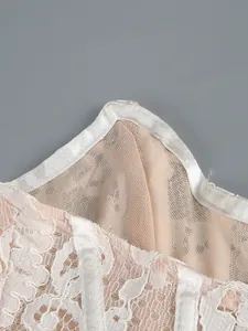 Close-up of white floral lace and beige mesh fabric detail on the elegant dress