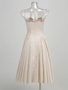 Back view of elegant beige spaghetti strap evening dress with pleated maxi skirt detail