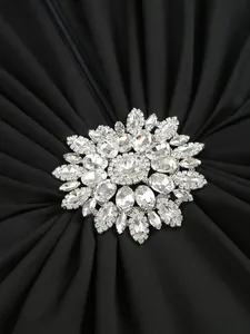 Macro view of sparkling crystal flower decoration on elegant black pleated evening dress