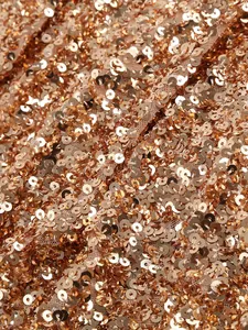 Macro close-up detail showing shimmering rose gold sequins on elegant mesh fabric dress