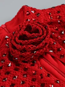 Detailed macro view of 3D rose flower and red rhinestone embellishments on mesh evening gown
