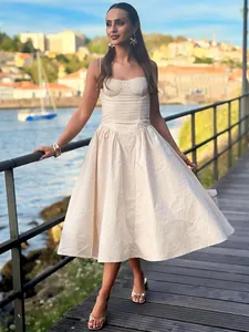 Full-length view of a beige corset-style midi dress on a model by the waterfront