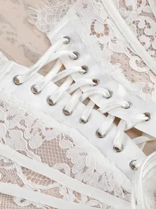 Close-up detail of white lace dress with elegant satin ribbon lacing and metal grommets