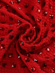 Detailed close-up of red textured evening gown fabric with sparkling square rhinestones