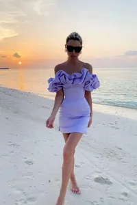Modelo con vestido corto lavanda con volantes y hombros descubiertos en la playa