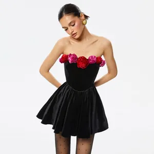 Professional shot of a black velvet strapless mini dress featuring 3D red floral details.