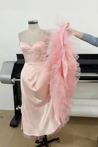 Detailed view of pink evening gown featuring voluminous ruffled tulle train and satin body