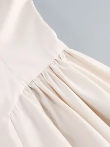 Macro detail showing the elegant pleating and fabric texture of the cream evening dress.