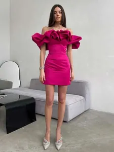 Vestido corto fucsia con hombros descubiertos y volantes muy elegantes.