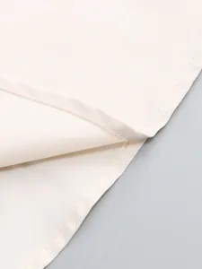 Detailed macro view of the delicate hem stitching and fine weave of this cream evening dress