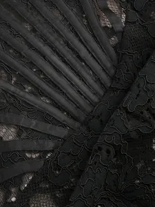 Detailed macro view of black floral lace and satin structural bands on a luxury dress
